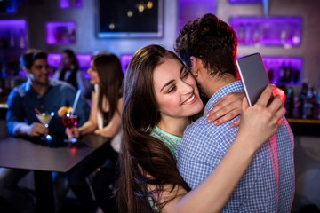 Woman checking her mobile phone while embracing a man