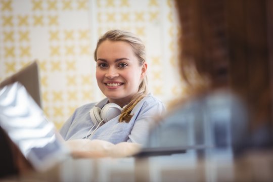 Smiling businesswoman with coworker using laptop