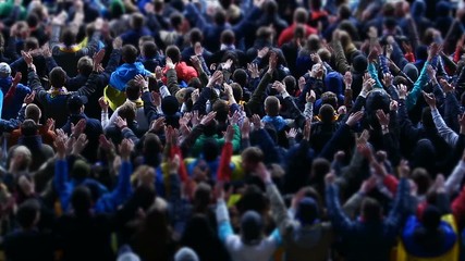 Football fans actively applauding and waving hands at stadium during match