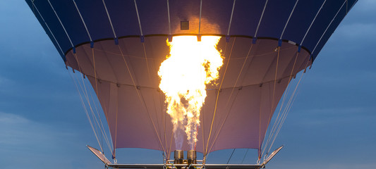 Inside of a colorful hot air balloon as it is inflated for flight, burning burner