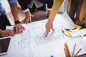 Businesswoman explaining blueprint to male colleagues