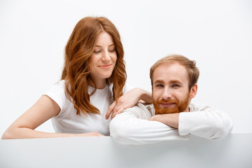 Funny redhead boy and girl posing at white table