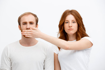 Seriously redhead girl  standing over white background and hide 