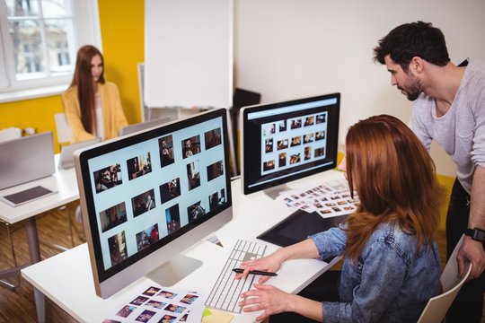 Female photo editor with coworkers working on computers