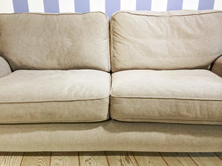 Beige sofa near the wall with striped wallpaper