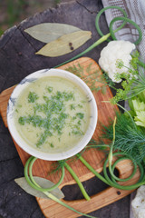 Bowl of green cream soup on wooden table