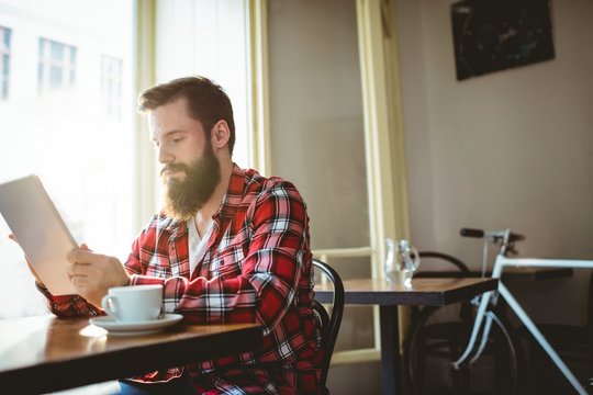 Hipster using tablet pc at cafe