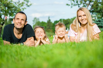 Portrait of happy parents with kids lying at the park