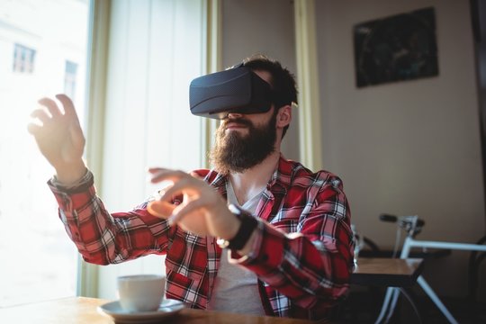Hipster using virtual reality headset at cafeteria