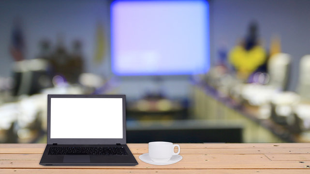 Laptop and coffee cup on wooden table with copy space and blurre