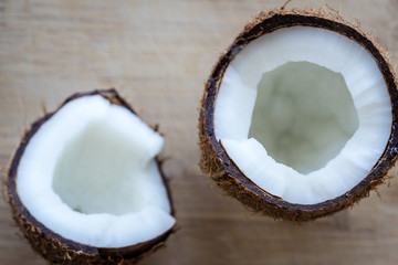 Top view of a cracked coconut on rustic wooden table background. Selective focus on one half of coconut.