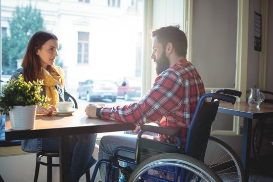 Disabled hipster with woman at cafe