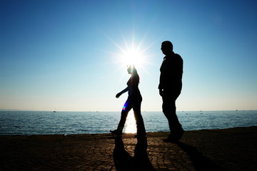 Fototapeta premium shillouettes of people a strolling at the beach