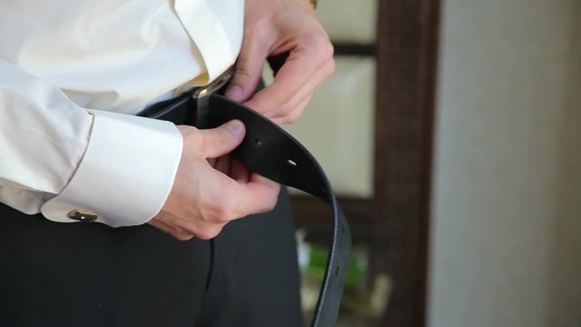 The groom buttoned the the belt of his trousers