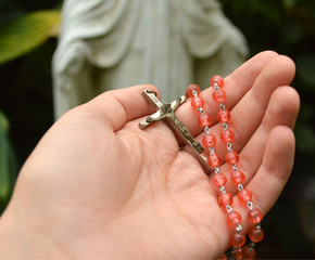 Pink rosary beads in woman's hand