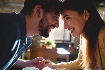 Side view of cheerful couple looking at each other in cafe