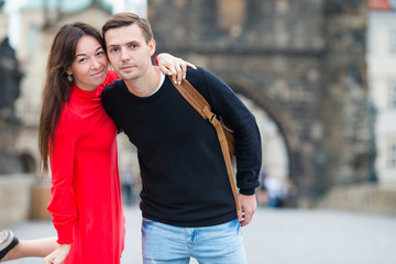 Happy couple walking on the Charles Bridge in Prague. Smiling lovers enjoying cityscape with famous landmarks.