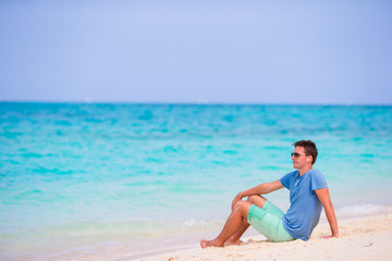 Young man enjoying the music on white sandy beach. Happy tourist relaxing on summer tropical vacation.