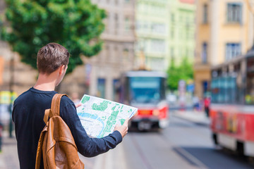 Young man with a city map and backpack in Europe. Caucasian tourist looking at the map of European city in search of attractions.