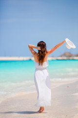 Fototapeta na wymiar Young beautiful woman on beach vacation. Happy girl enjoy beach and warm weather while walking along the ocean