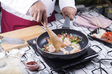 Chef stir chicken in the pan for cooking