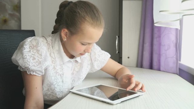 Teenager girl uses a digital tablet at the desk