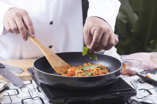 Chef putting basil to pan for cooking spaghetti chicken sauce