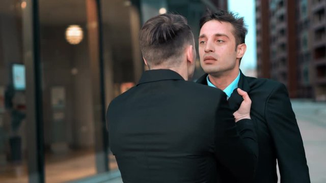Angry Young businessman grabbing his colleague by the lapels of suite. He want to start fighting. Hard conversation and debate. Boss work with smartphone and dismiss his subordinate. Glass business