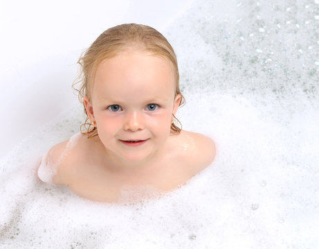 Wet baby girl toddler kid in bathing with soap suds in white bat