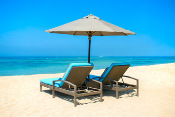 Two lounge chairs with sun umbrella on a beach