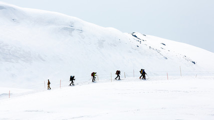 Fototapeta na wymiar Skiers walking on snow covered mountain ranges