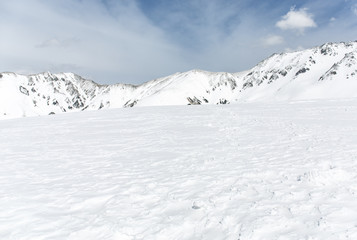 Fototapeta na wymiar Rocks on the snow covered mountain under blue sky