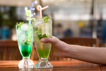 Woman holding a fresh green lemon soda drink