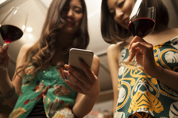 Young women looking at a smart phone with a glass of wine at the bar