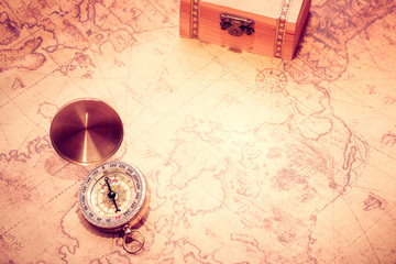 Compass on vintage map and treasure chest