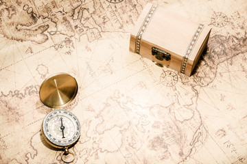 Compass on vintage map and treasure chest