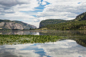 Fototapeta na wymiar Reflections on a lake on a mountainous area. Taken near Kelowna, British Columbia, Canada.