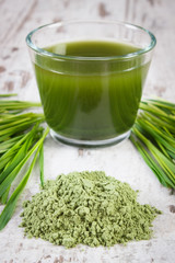 Heap of young powder barley, barley grass and beverage on old wooden background
