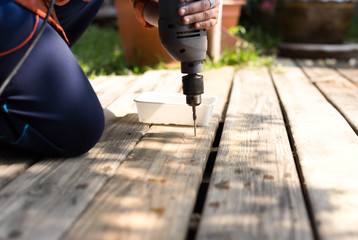 Carpenter using drill on wooden floor