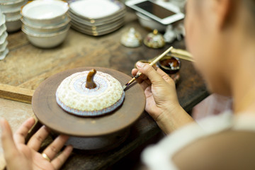 Female hands a brush painted a colorful ceramic cup