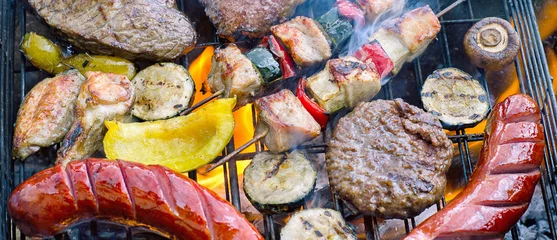Garden poster Grill / Barbecue Assorted meat with vegetables cooking on a grill with flames