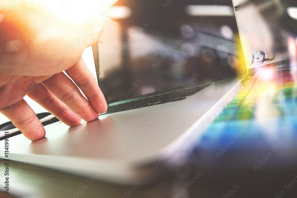 Poster close up of designer hand working with laptop computer on wooden