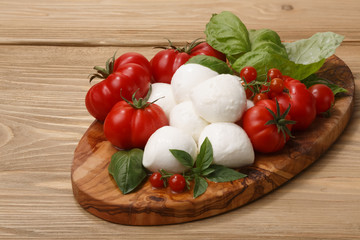 Mozzarella, heirloom tomatoes, basil leaves on a wooden serving