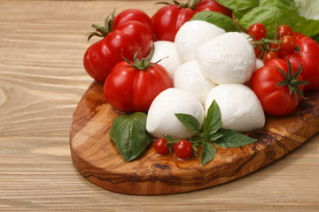 Mozzarella, heirloom tomatoes, basil leaves on a wooden serving