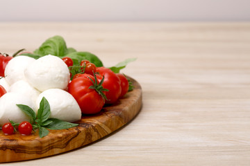 Mozzarella, heirloom tomatoes, basil leaves on a wooden serving