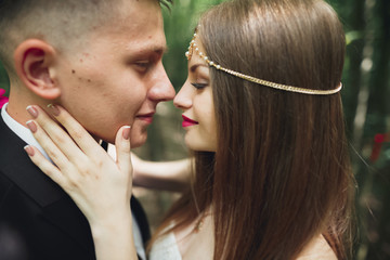 Beautiful young wedding couple is kissing and smiling in the park