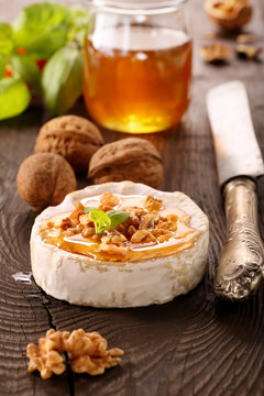 Grilled brie cheese with honey and nuts on old wooden background