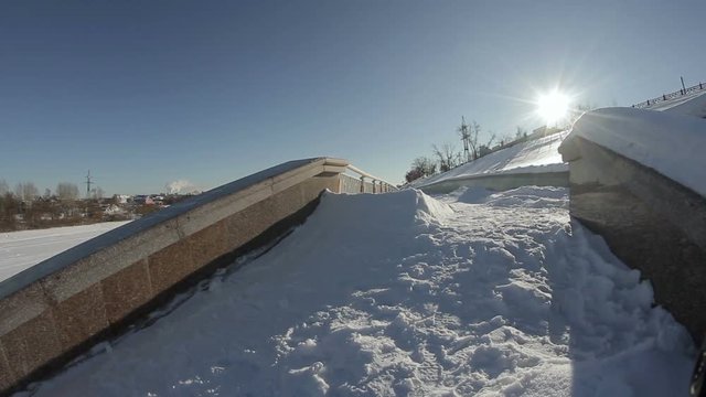 Snowboarder goes near the street ladge on the sun background