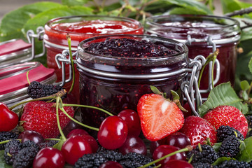 strawberry, cherry and mulberry jam on a rustic table