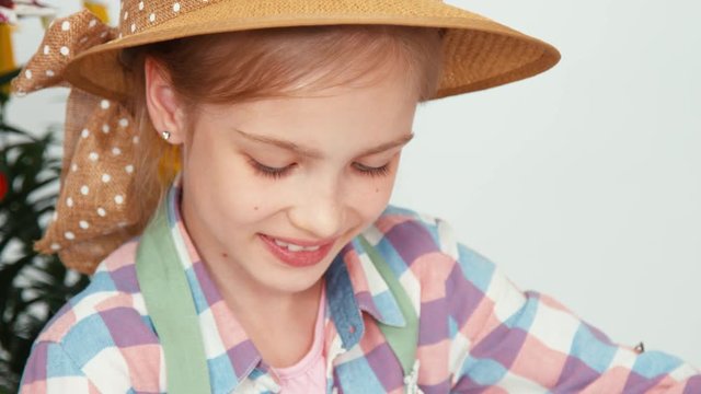 Extreme close-up portrait child girl in hat sitting and drawing butterfly on drawing board and smiling with teeth at camera